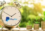 Clock with PayPal logo next to stack of coins