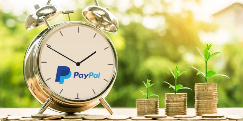 Clock with PayPal logo next to stack of coins