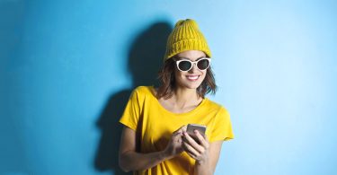 Woman wearing yellow taking an online survey on her phone