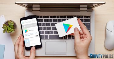 Woman holding Google Play gift card while using phone and laptop
