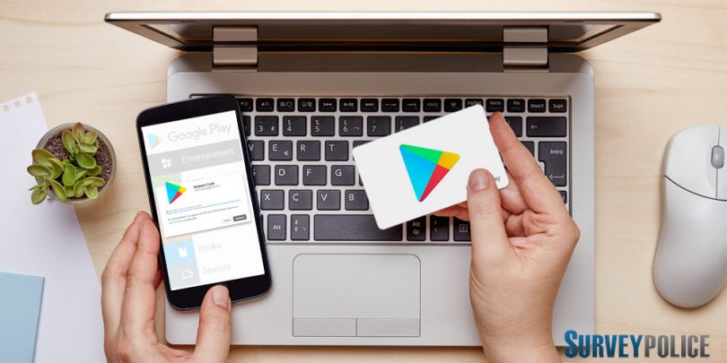 Woman holding Google Play gift card while using phone and laptop