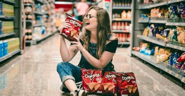 Woman sitting on floor of CVS holding chips