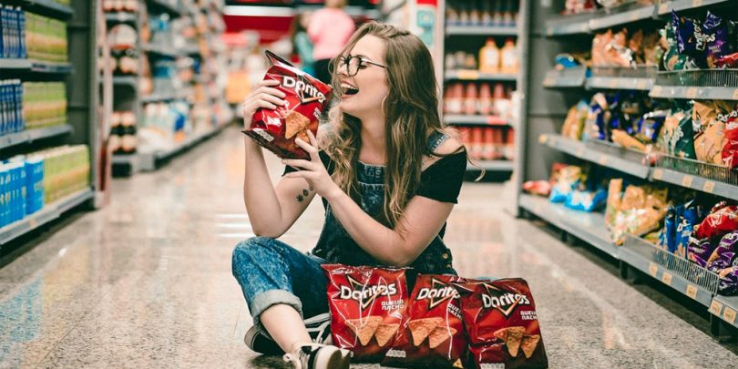 Woman sitting on floor of CVS holding chips