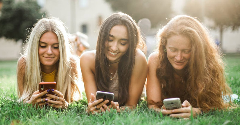 Teens looking at social media on their phones