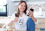 Woman in kitchen looking at surveys on her phone