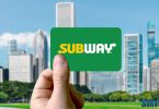 Holding subway gift card against cityscape