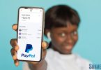 Woman holding phone with $100 PayPal account