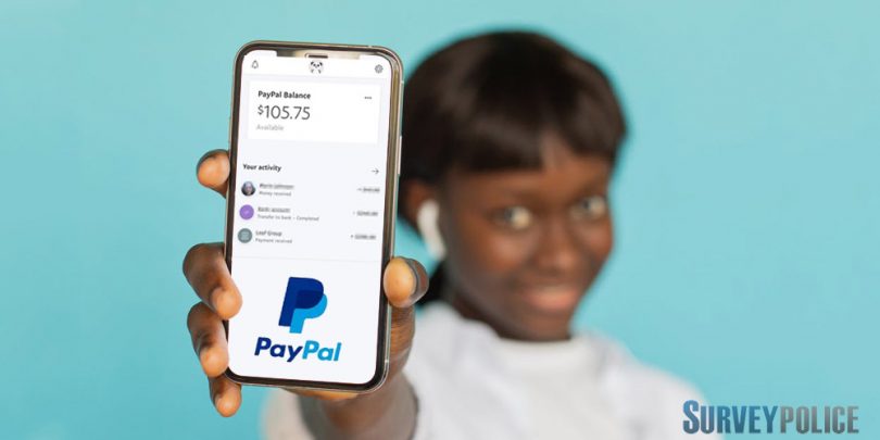 Woman holding phone with $100 PayPal account